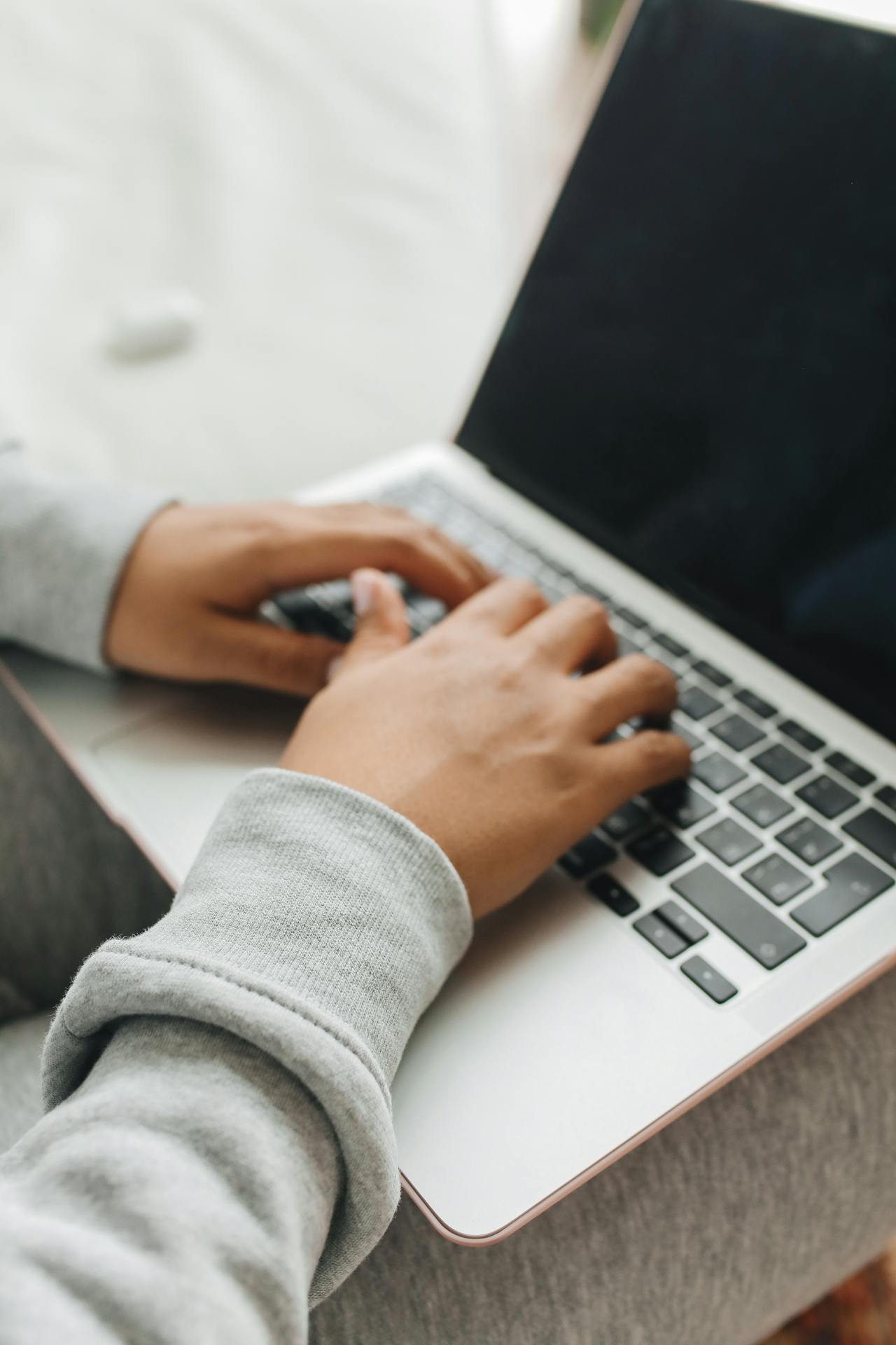 primer plano de las manos de una persona apoyadas en el teclado de un portátil