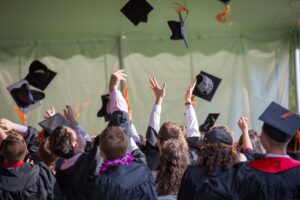 un grupo de universitarios lanzando sus sombreros celebrando su graduación